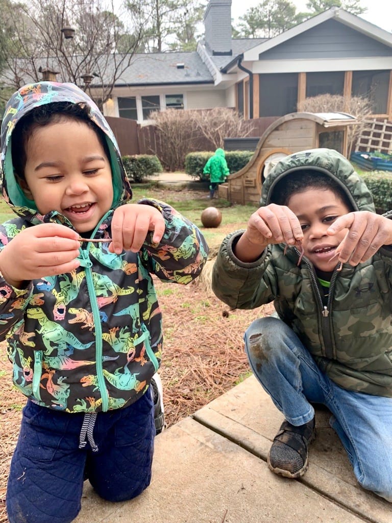 two children outside playing with worms